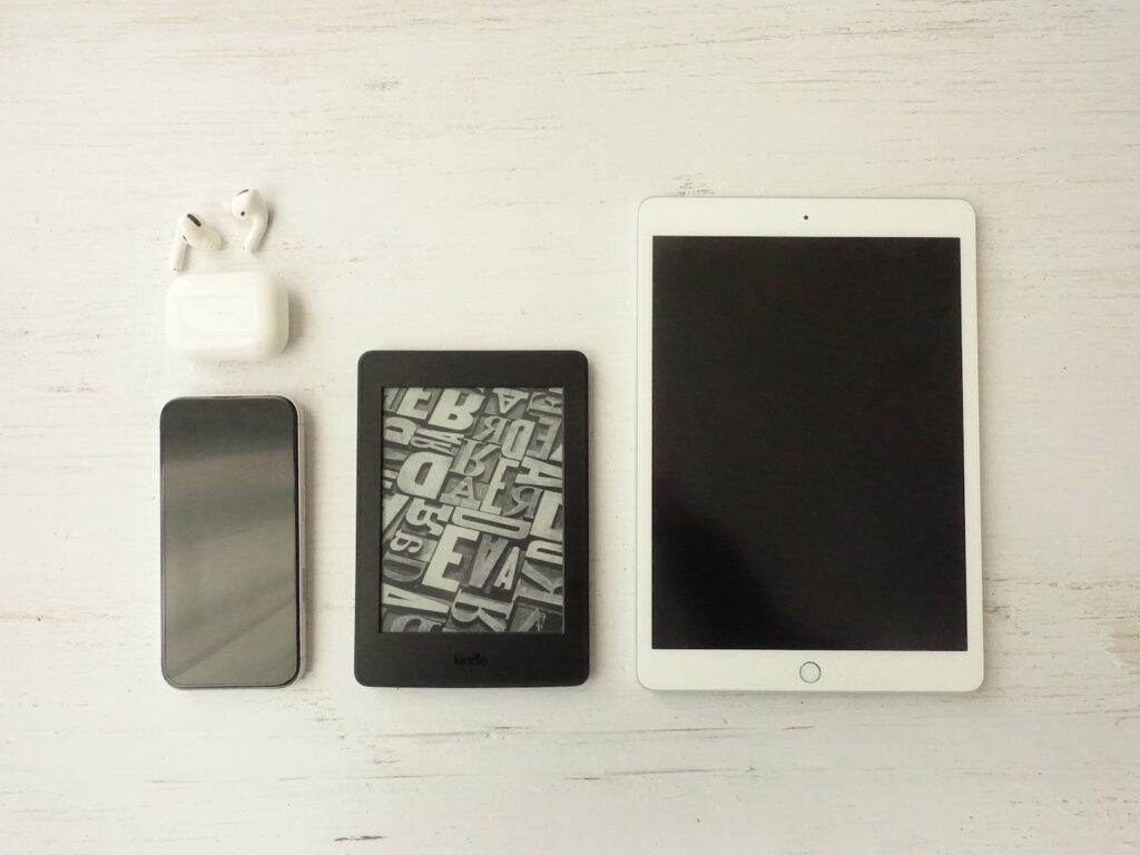 AirPods Pro、iPhone、Kindleリーダー、iPadを並べて置いた様子。